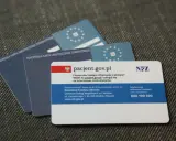 Kilka kart EKUZ i karta pacjenta NFZ na szarym tle.
