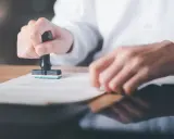 Osoba stempluje dokument. Prace interwencyjne wady i zalety mogą być związane z formalnościami.