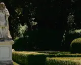 Statua romana domina la scalinata nei **Horti Leonini**. Giardini curati e alberi ombrosi creano un'atmosfera regale.