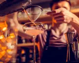 Un barman verse un cocktail d'un shaker dans un verre. C'est ainsi qu'un shaker sert à mélanger et refroidir les boissons.