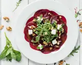 Rote Bete Carpaccio vegan mit Rucola, Walnüssen und veganem Feta auf weißem Teller.