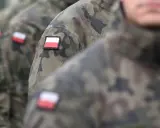 Żołnierze w mundurach moro, z polskimi flagami na ramionach, czekają na swoją emeryturę wojskową.