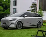 Le Xpeng X9, un monospace argenté futuriste, est garé sur une pelouse verte devant un bâtiment moderne.