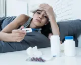 Donna malata a letto con termometro e medicine, preoccupata per i ciproxin effetti collaterali.