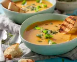 Zwei Schalen cremiger Kürbissuppe mit geröstetem Brot und Kürbiskernen. Ein leichtes, magenschonendes Essen, perfekt für kühle Tage.