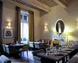 Salle à manger élégante avec tables dressées, fauteuils confortables et un miroir orné. L'ambiance évoque une **spécialité provençale** raffinée.