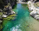 Una espectacular piscina natural en Extremadura, con aguas cristalinas y gente disfrutando del baño entre rocas y vegetación.