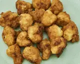 Chrupiące kawałki kalafiora w panierce, ułożone na jasnoszarym talerzu. Idealna przekąska dla każdego.