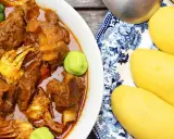 Un plat de foutou sauce graine avec de la viande et du crabe, accompagné de boules de pâte jaune sur une assiette décorée.