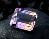 Un taglio a smeraldo sfaccettato mostra la transizione tra ametista e quarzo rosa, un connubio di colori su una roccia scura.