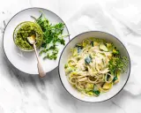 Pyszny makaron z cukinią w kremowym sosie, obok miseczka pesto i świeże zioła. Idealny lekki posiłek.