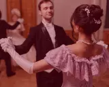 Elegancka para tańczy powolny walc na balu. Ona w pastelowej sukni, on w fraku.