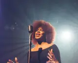 Kobieta z burzą afro włosów śpiewa do mikrofonu, jej głos jest niczym unchained melody, wolny i pełen emocji.