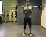 Mann macht Langhantel Curls im Fitnessstudio. Er trainiert seine Bizeps.