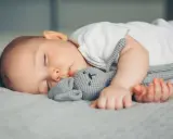 Ein Baby schläft friedlich mit seinem Häschen-Spielzeug. Vielleicht ist es die berüchtigte 4 monats schlafregression, die es so müde macht.