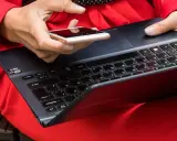 Besorgte Person prüft ihr Smartphone, nachdem ihr t-online Mail gehackt wurde. Sie hält es über eine Tastatur.