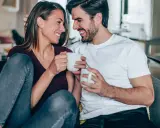 Para jak **byk** i **ryby** w akwarium, śmieją się, trzymając kubki.