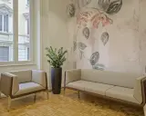Eleganckie fotele i sofa na tle tapety z motywem kwiatowym. Czy można kleić tapetę na tapetę? Tutaj wygląda to stylowo.