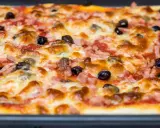 Une pizza rectangulaire garnie de jambon, d'olives et de fromage fondant. Parfait pour savoir que faire avec une pâte à pizza rectangulaire !