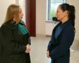 Prawniczka w todze rozmawia z kobietą w granatowym płaszczu.