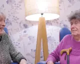 Dwie starsze panie rozmawiają, śmiejąc się. Ich uśmiechy sugerują, że znają sekret, jak utrzymać związek.