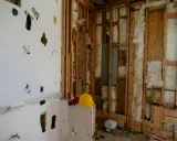 Chantier en cours, murs ouverts révélant l'isolant. Attention, la laine de bois peut présenter un danger si mal manipulée. Casque et gants de protection à proximité.