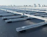 Monteringssystem för solpaneler på ett platt tak. Aluminiumprofiler lyfts upp av svarta fötter, redo för installation.