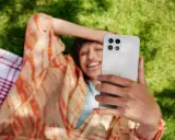 Uśmiechnięta osoba robi selfie na trawie, ciesząc się czasem przed ekranem.