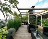 Un accogliente terrazzo rustico con mobili neri, un giardino verticale e piante rigogliose, ideale per rilassarsi.