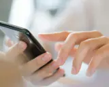Dłonie wpisują numer referencyjny przesyłki na ekranie smartfona.