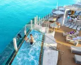 Coppia in jacuzzi su nave da crociera Caraibi, con bar e lettini prendisole. Un sogno di volo e crociera Caraibi.