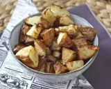 Patate dorate e croccanti in friggitrice ad aria, servite in una ciotola su carta di giornale.