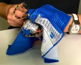 Brille mit buntem Rahmen wird mit einem blauen Tuch gereinigt. So lässt sich Haarspray von Brille entfernen.