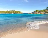 Türkisfarbenes Meer, Sandstrand und felsige Küste mit einem kleinen Haus auf Mallorca.