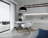 Interni luminosi di una casa di design con cucina moderna, tavolo rotondo e sedie bianche. Si intravede un terrazzo con piante.