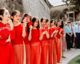 Novias y damas de honor con trajes rojos tradicionales, sosteniendo sobres rojos, celebrando una boda china.