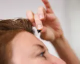 Dłoń trzyma kapsułkę z serum. To celimax retinal shot, który zaraz zostanie zaaplikowany na skórę.