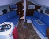 Intérieur du JOD 35, avec banquettes bleues, évier en inox et parquet en bois. Prêt pour une nouvelle aventure en mer.
