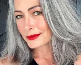 Donna con splendidi capelli grigi, labbra rosse vivaci e uno sguardo intenso.