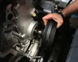 Mano retirando la polea del cigüeñal rota de un motor.
