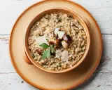 Un cremoso risotto ai funghi, un clásico plato italiano, servido en un cuenco de cerámica.