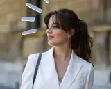 Frauen mit Curtain Bangs stylen ihre Haare lässig zu einem Pferdeschwanz. Der weiße Blazer unterstreicht den eleganten Look.