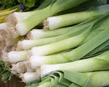 Un montón de puerros frescos, listos para deliciosas recetas con puerro. Sus tallos blancos y verdes prometen sabor.