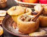 Manzanas asadas rellenas de pasas y canela, espolvoreadas con azúcar glas. Un postre casero y reconfortante.