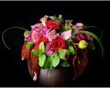 Un bouquet de roses rouges, callas roses et fleurs violettes dans un vase sombre. La signification des fleurs est souvent liée à l'amour et à la passion.
