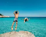 Due ragazzi si tuffano in un mare cristallino, un'idea perfetta per chi cerca dove andare in vacanza con pochi soldi in Italia.