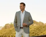 A man in a light grey blazer, striped shirt, and beige pants. This is a stylish option for what to wear to an engagement party.