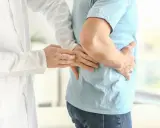 Lekarz bada pacjenta z bólem w boku, sugerującym rozbijanie kamieni nerkowych.