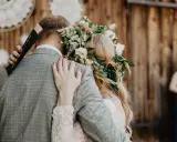 Para młoda w uścisku, panna młoda ma piękny wianek ślubny z kwiatów i traw.