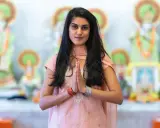 En ung kvinna i traditionella kläder med händerna i bön framför hinduiska statyer, en bild som väcker tankar om mantra hinduism.